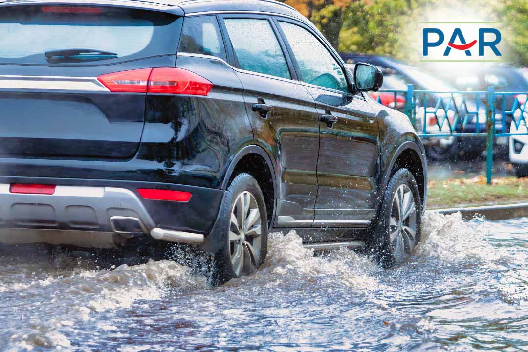 Mobil melintas di jalan basah saat hujan menggambarkan risiko aquaplaning